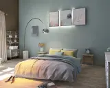 La couleur mur chambre parentale est un bleu-vert doux, créant une ambiance apaisante. Le lit est orné de coussins jaunes et d'une couverture grise.