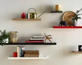 Étagères flottantes décorées : plante, arrosoir doré, livres, éléphant, bougie. La hauteur entre étagère varie pour un design dynamique.