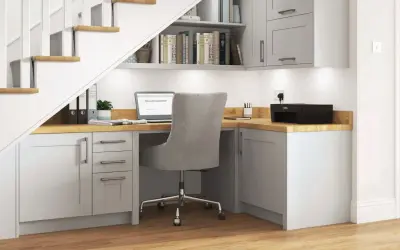 Bureau sous escalier fonctionnel avec ordinateur portable, imprimante et rangements.