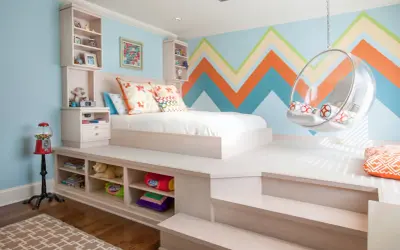 Chambre fille petit espace avec lit sur estrade, rangements intégrés, fauteuil bulle et mur géométrique coloré.