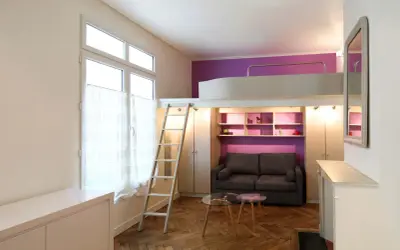 Un studio optimisé de plan 20m2 avec lit mezzanine, canapé, étagères violettes et échelle.