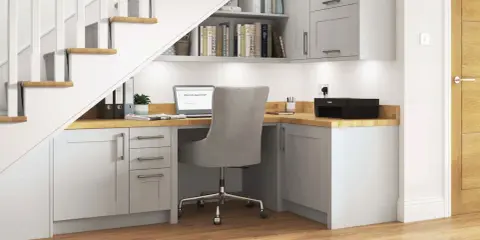 Bureau sous escalier fonctionnel avec ordinateur portable, imprimante et rangements.
