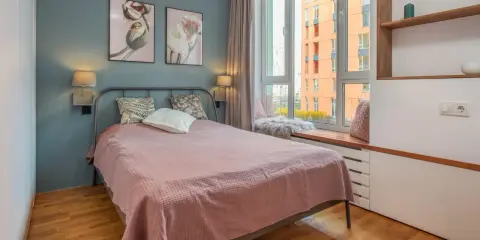 Une chambre d'amis confortable avec un lit douillet, des tableaux de fleurs et une vue sur la ville.