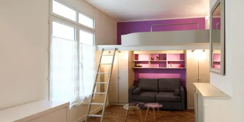 Un studio optimisé de plan 20m2 avec lit mezzanine, canapé, étagères violettes et échelle.