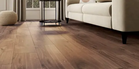 Un salon lumineux avec un nouveau revêtement sol en bois chaleureux, un canapé crème et des coussins décoratifs.