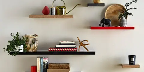 Étagères flottantes décorées : plante, arrosoir doré, livres, éléphant, bougie. La hauteur entre étagère varie pour un design dynamique.