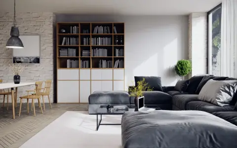 Un salon moderne avec un grand canapé d'angle gris foncé, une bibliothèque remplie de livres, une table basse et une table à manger en bois clair.