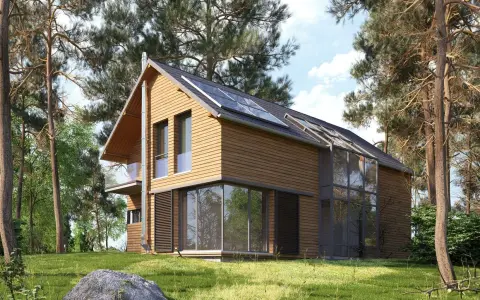 Maison en bois moderne avec panneaux solaires, conçue par un constructeur maison écologique. Entourée de pins, elle s'intègre parfaitement à la nature.