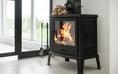 Poêle à bois en fonte avec flammes vives, pile de bois et accessoires. Idéal pour un couplage pompe à chaleur et poêle bois pour une chaleur optimale.