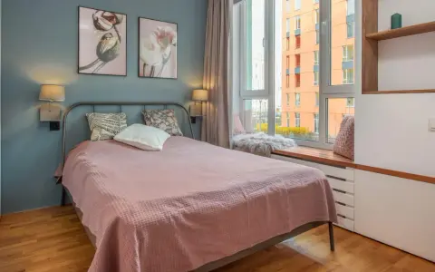 Une chambre d'amis confortable avec un lit douillet, des tableaux de fleurs et une vue sur la ville.