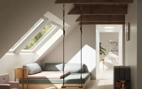 Aménagement comble 1m50 : un espace cosy avec balançoire, lit bas et vue sur la nature par les fenêtres de toit.