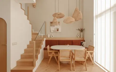 Plan salle à manger avec banquette, table ovale et chaises en rotin. Escalier en bois à gauche.