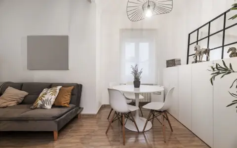 Idée pour aménager salon salle à manger 20m2 : canapé gris, table ronde blanche avec chaises, et rangements muraux.