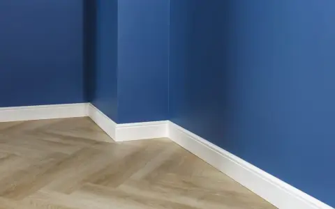 Un coin de pièce aux murs bleu profond, avec un parquet imitation bois clair et un élégant type de plinthe blanc.