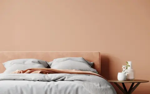 Lit de chambre douillet avec mur et tête de lit couleur pêche. Quelle couleur chambre pour une ambiance chaleureuse et apaisante.
