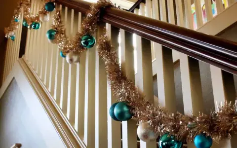 Guirlande dorée et boules de Noël bleues et blanches pour décorer une rampe d'escalier pour Noël.
