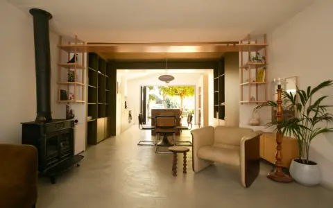 Espace de vie lumineux en enfilade : salon avec poêle, salle à manger et cuisine ouvrant sur le jardin.