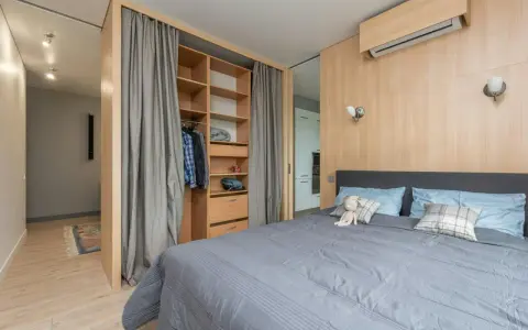 Chambre moderne avec lit douillet, dressing ouvert et rideaux gris. Le prix pour peindre une chambre de 12m2 dépend des finitions.