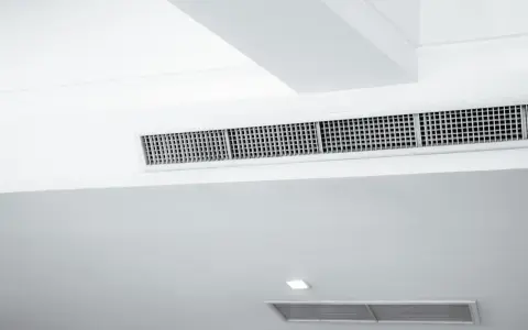 Grille de climatisation par le plafond, discrète et intégrée dans un design moderne pour un confort optimal.