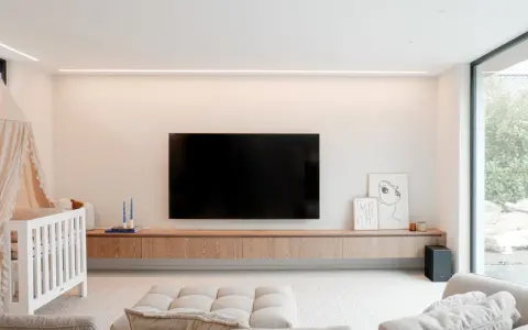 Meuble TV en bois clair, suspendu, offrant une belle profondeur. Une télévision est fixée au mur au-dessus.