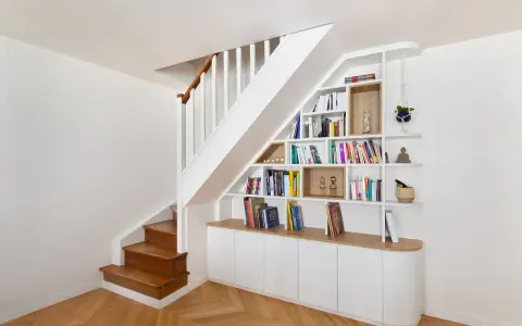 Bibliothèque intégrée dans la cage d'escalier, offrant un espace de rangement astucieux et décoratif.