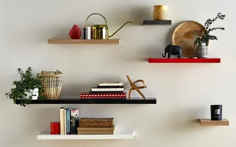 Étagères flottantes décorées : plante, arrosoir doré, livres, éléphant, bougie. La hauteur entre étagère varie pour un design dynamique.