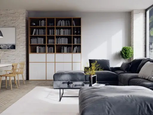 Un salon moderne avec un grand canapé d'angle gris foncé, une bibliothèque remplie de livres, une table basse et une table à manger en bois clair.