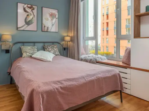 Une chambre d'amis confortable avec un lit douillet, des tableaux de fleurs et une vue sur la ville.