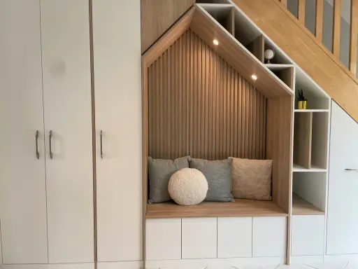 Aménagement cage d'escalier avec banquette confortable, coussins douillets et rangements intégrés.