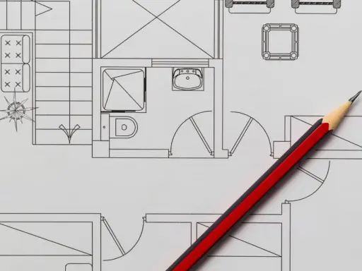 Un crayon rouge et noir sur un plan de maison, idéal pour faire un plan de maison gratuit et visualiser votre projet.