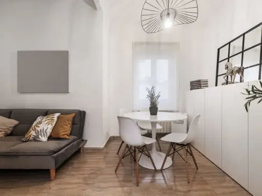 Idée pour aménager salon salle à manger 20m2 : canapé gris, table ronde blanche avec chaises, et rangements muraux.