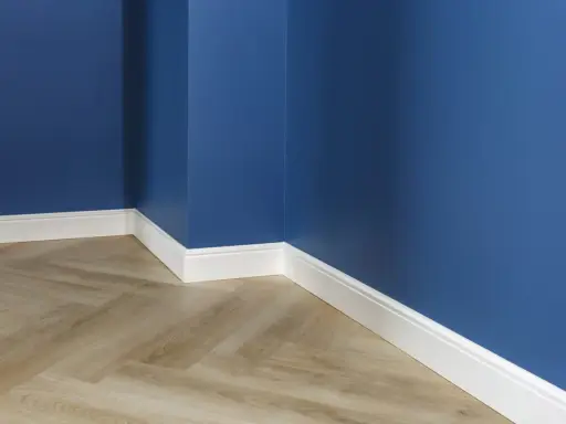 Un coin de pièce aux murs bleu profond, avec un parquet imitation bois clair et un élégant type de plinthe blanc.