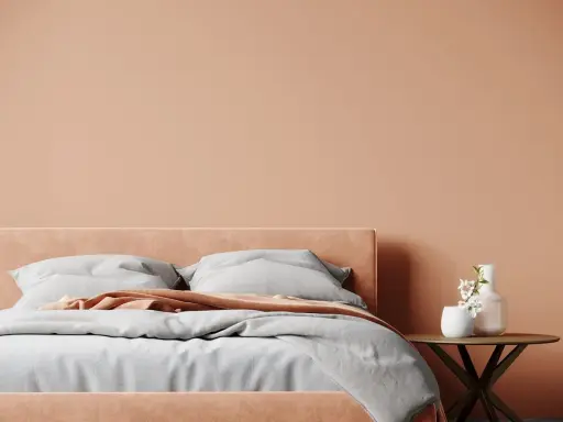 Lit de chambre douillet avec mur et tête de lit couleur pêche. Quelle couleur chambre pour une ambiance chaleureuse et apaisante.