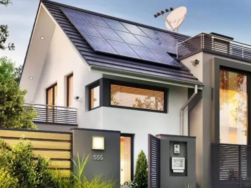 Une maison passive moderne avec des panneaux solaires sur le toit, une clôture en bois et une boîte aux lettres.