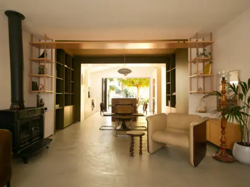 Espace de vie lumineux en enfilade : salon avec poêle, salle à manger et cuisine ouvrant sur le jardin.