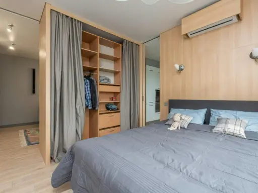 Chambre moderne avec lit douillet, dressing ouvert et rideaux gris. Le prix pour peindre une chambre de 12m2 dépend des finitions.