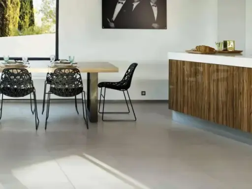 Un salon moderne avec un carrelage pièce de vie tendance, une table en bois, des chaises noires design et un îlot de cuisine en bois veiné.