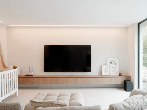 Meuble TV en bois clair, suspendu, offrant une belle profondeur. Une télévision est fixée au mur au-dessus.