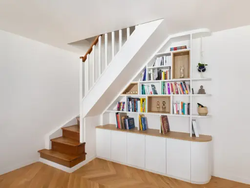 Bibliothèque intégrée dans la cage d'escalier, offrant un espace de rangement astucieux et décoratif.