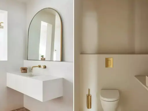 Idées pour décorer ses toilettes : un lavabo suspendu blanc, un miroir arche doré, une chasse d'eau dorée et une brosse WC assortie.
