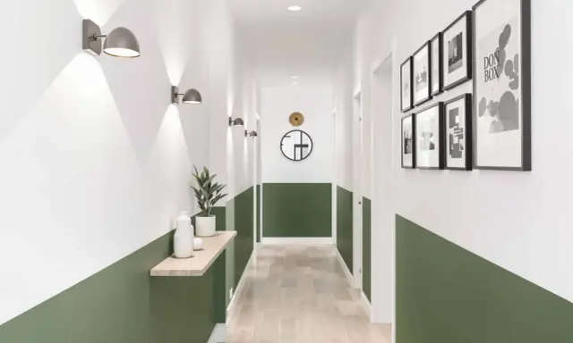 Un couloir moderne avec un soubassement vert, des appliques murales, une étagère en bois et des cadres photo.
