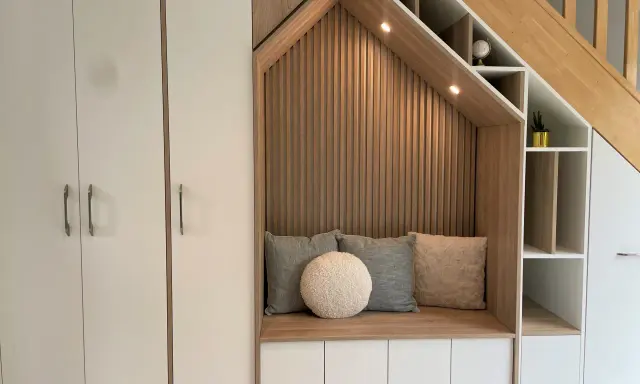Aménagement cage d'escalier avec banquette confortable, coussins douillets et rangements intégrés.