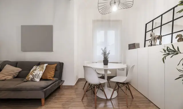 Idée pour aménager salon salle à manger 20m2 : canapé gris, table ronde blanche avec chaises, et rangements muraux.