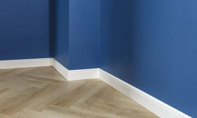 Un coin de pièce aux murs bleu profond, avec un parquet imitation bois clair et un élégant type de plinthe blanc.
