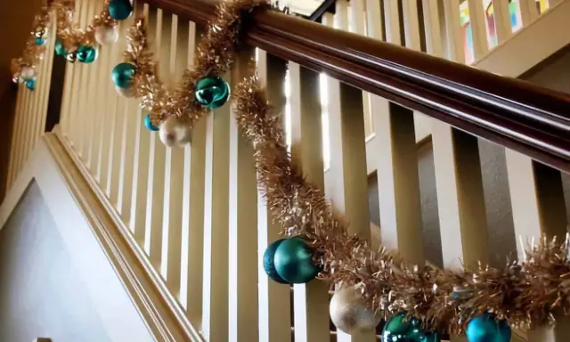 Guirlande dorée et boules de Noël bleues et blanches pour décorer une rampe d'escalier pour Noël.