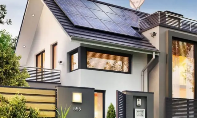 Une maison passive moderne avec des panneaux solaires sur le toit, une clôture en bois et une boîte aux lettres.