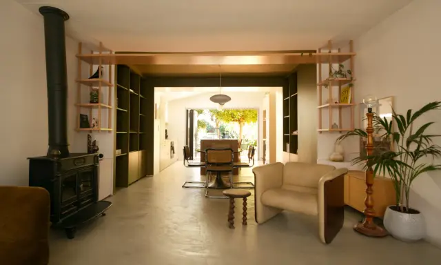 Espace de vie lumineux en enfilade : salon avec poêle, salle à manger et cuisine ouvrant sur le jardin.