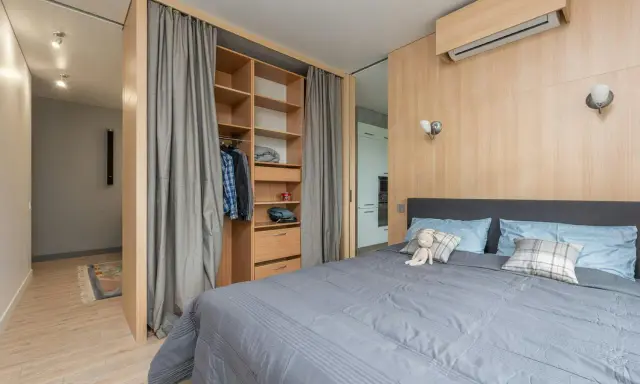 Chambre moderne avec lit douillet, dressing ouvert et rideaux gris. Le prix pour peindre une chambre de 12m2 dépend des finitions.