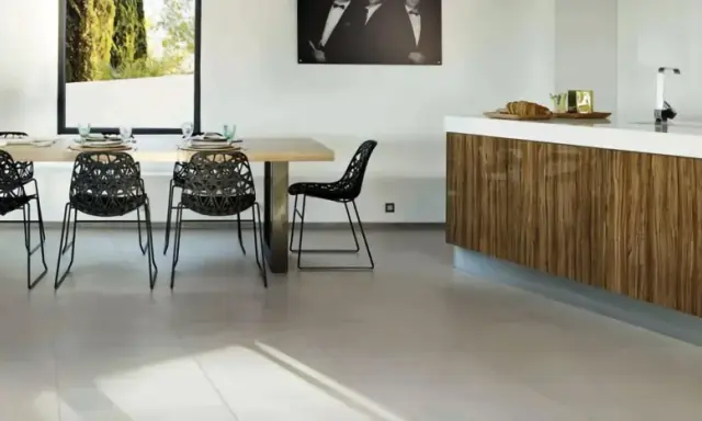Un salon moderne avec un carrelage pièce de vie tendance, une table en bois, des chaises noires design et un îlot de cuisine en bois veiné.