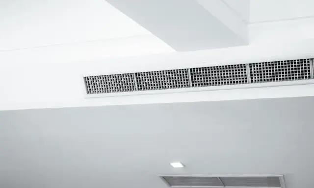 Grille de climatisation par le plafond, discrète et intégrée dans un design moderne pour un confort optimal.